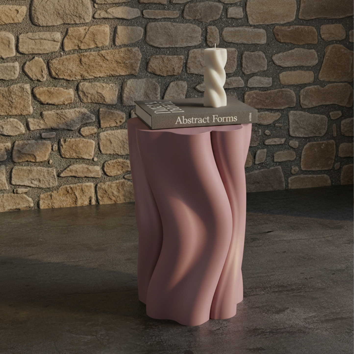 Pink Dune Side Table by Namami Studio with a book titled 'Abstract Forms' and a sculpture against a stone wall.