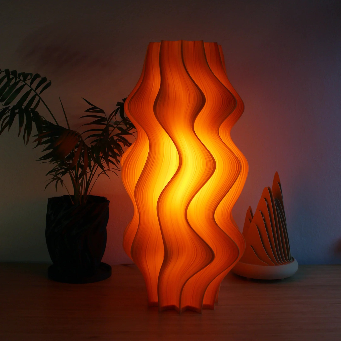 Large Iris Lamp in mandarin orange, 52cm tall with pleated sculptural form and soft glow.