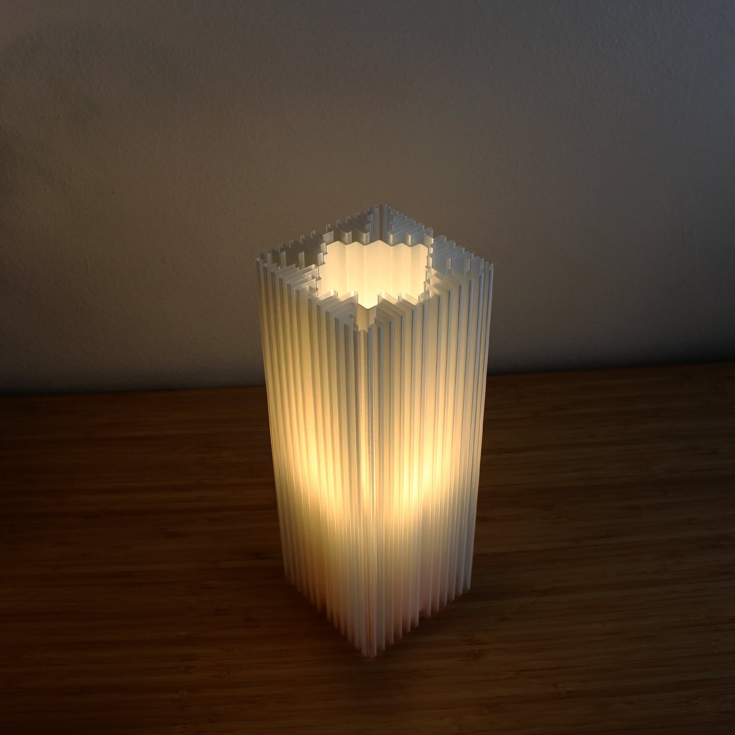 Minimalist shard lamp on wooden surface, capturing depth and rhythm in design.
