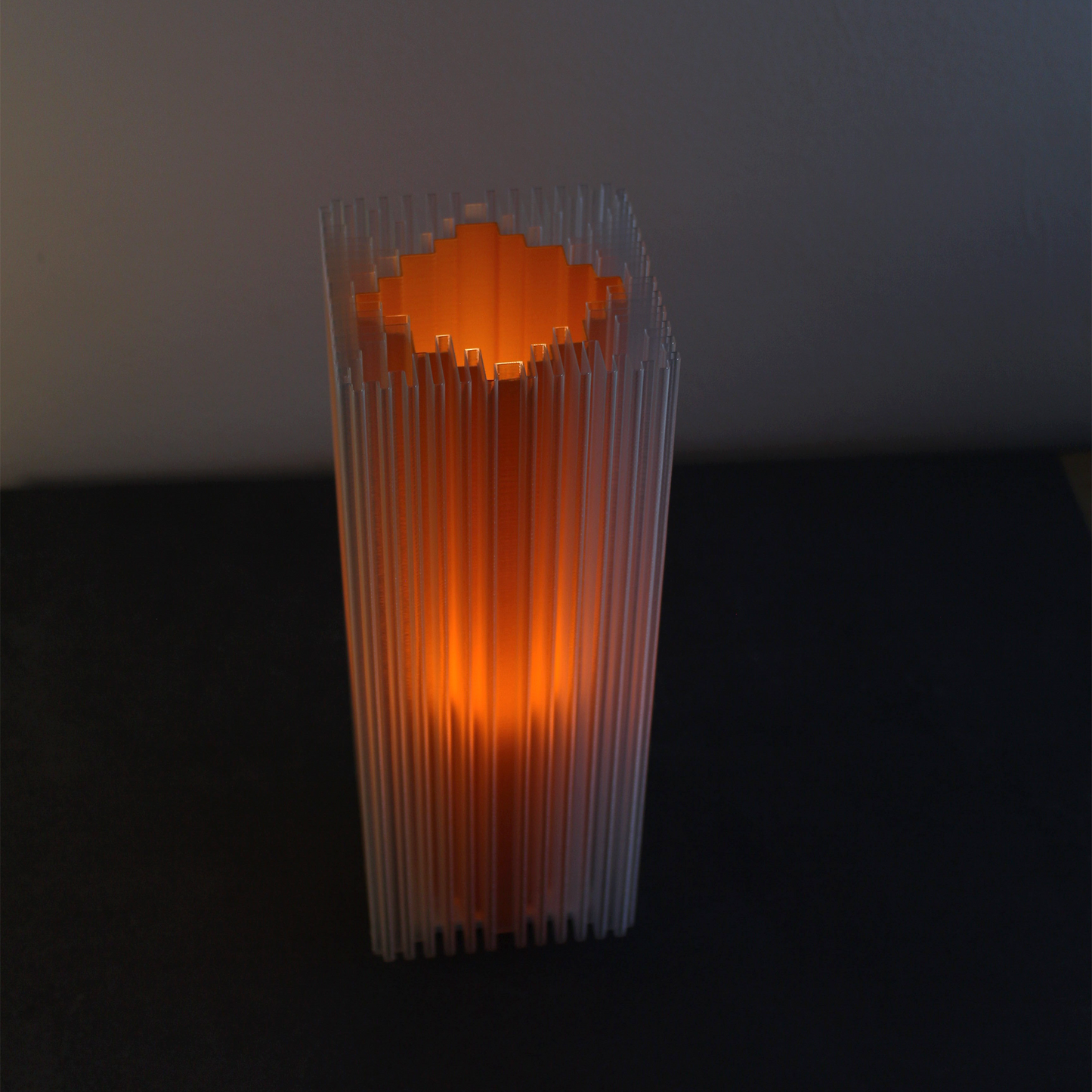 Lamp with shard-inspired vertical texture, soft orange glow radiating through layered ridges.