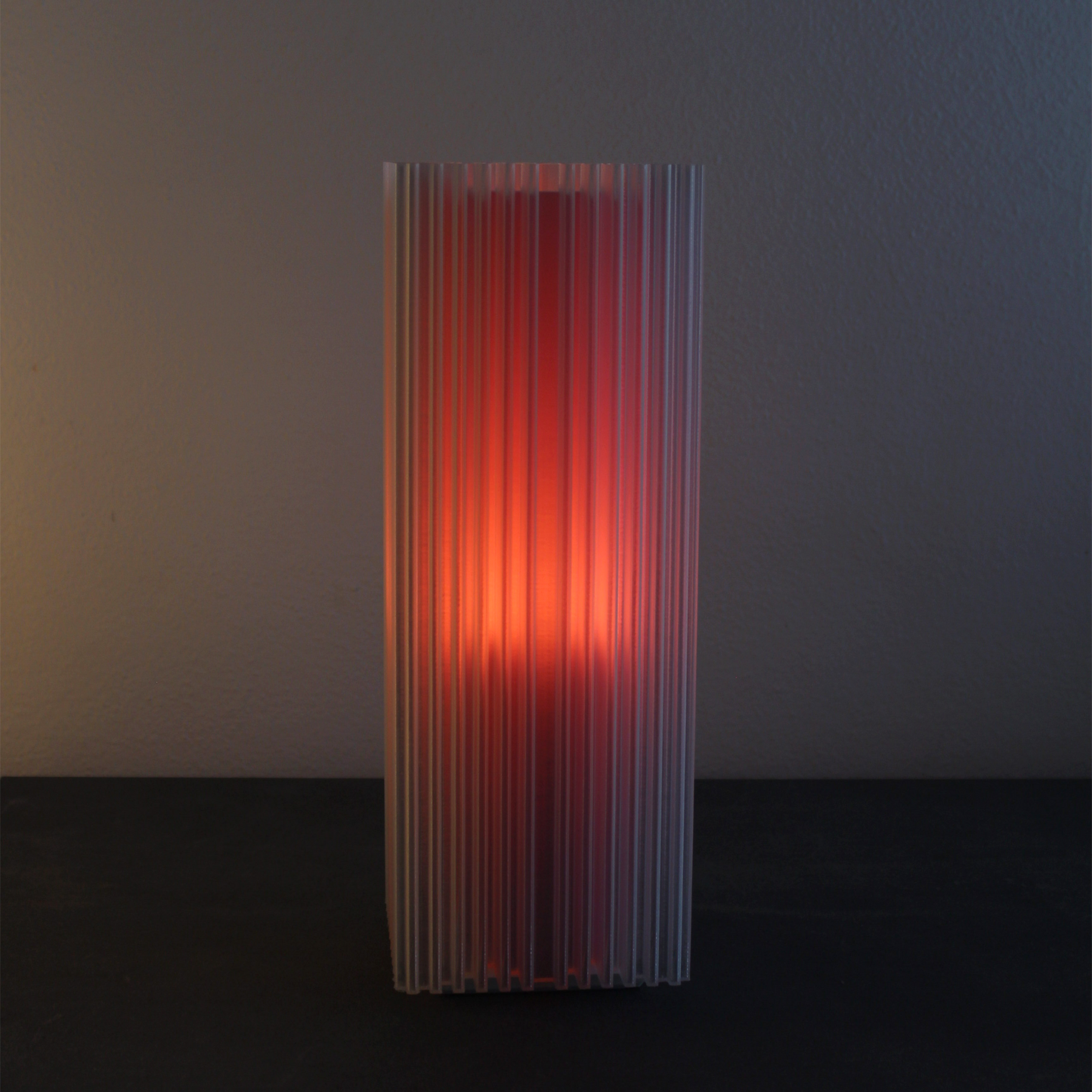 Tall, ribbed Shard Lamp with a gradient of Flamingo on a dark background