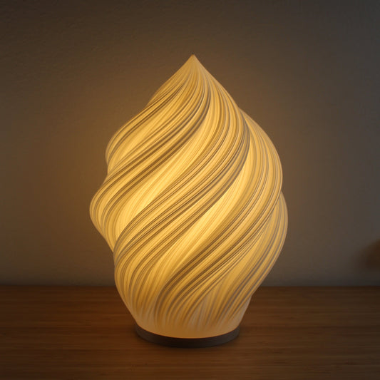 Soft Serve Lamp in white, 3D-printed with swirling ice cream–inspired design, glowing warmly on a side table.