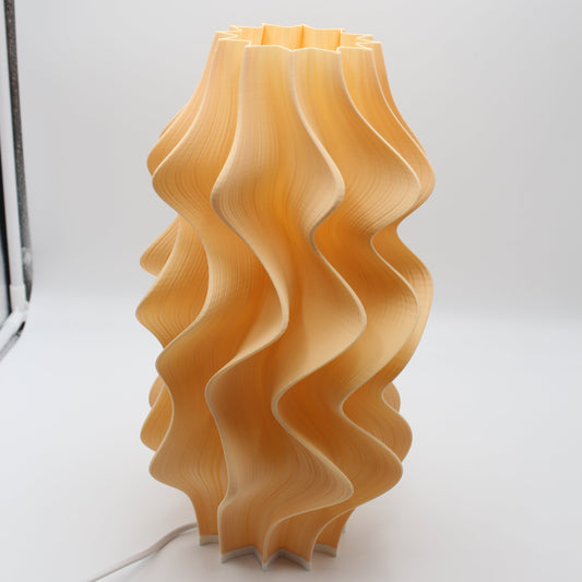 A close-up of the light orange Iris Lamp, highlighting its soft tone and pleated texture.