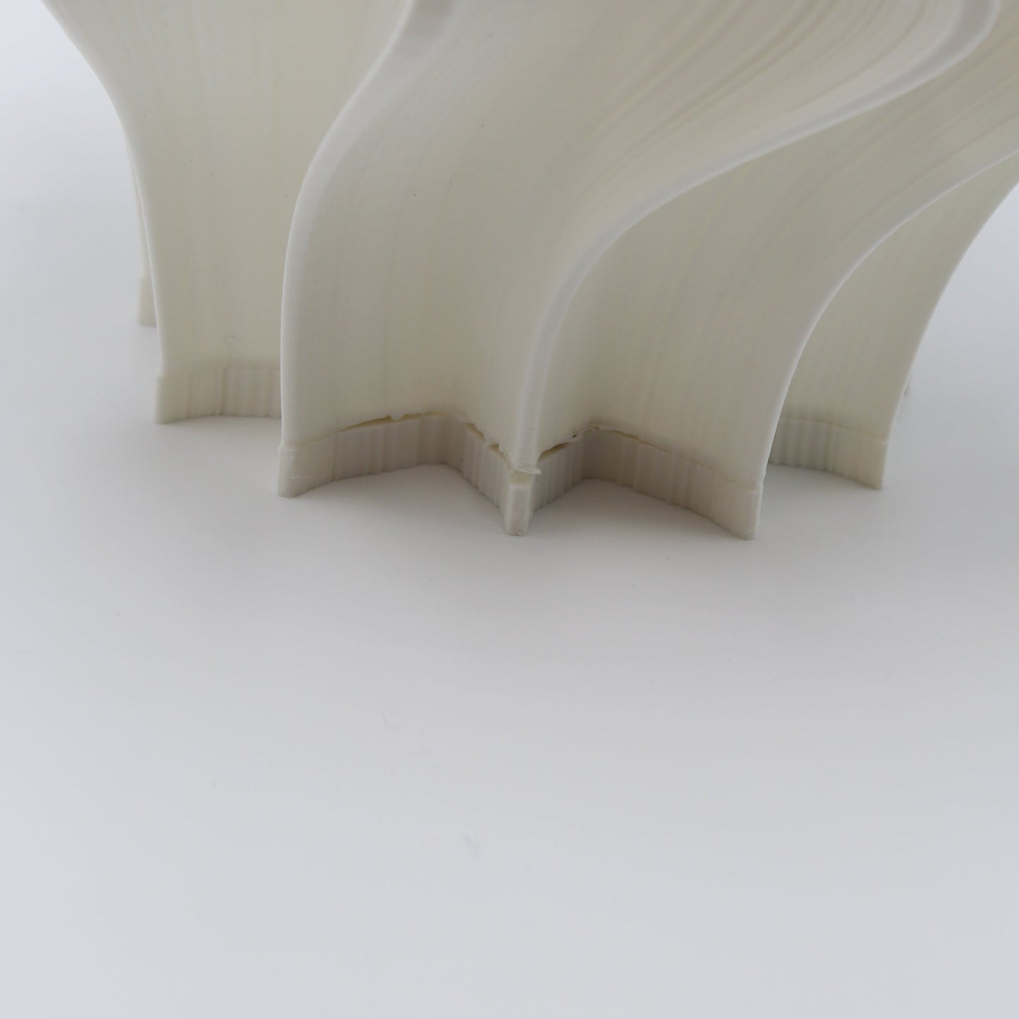 Close-up of a Iris creme lamp with wavy design on a light gray background