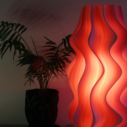Wavy red lamp on a table with plants in the background