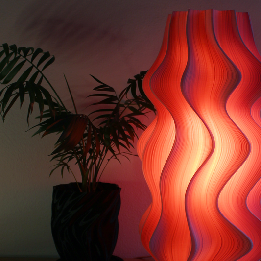 Wavy red lamp on a table with plants in the background