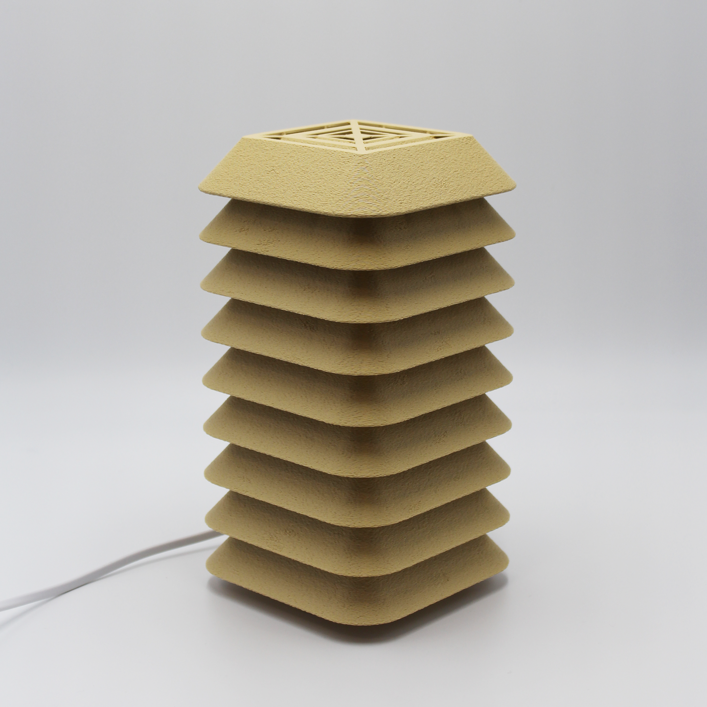 Side profile of the Kengo Tō lamp showing its precise stacked layers and sand-colored textured finish