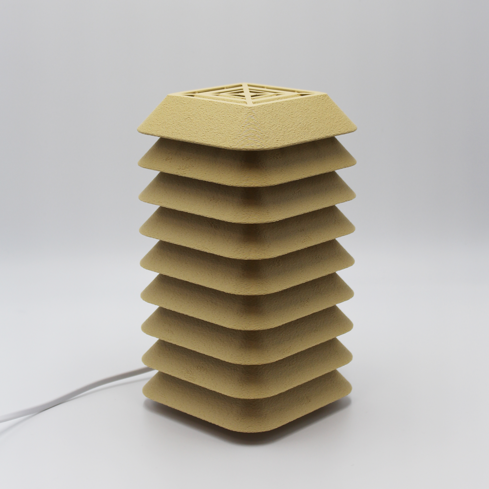 Side profile of the Kengo Tō lamp showing its precise stacked layers and sand-colored textured finish
