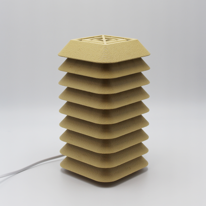 Side profile of the Kengo Tō lamp showing its precise stacked layers and sand-colored textured finish