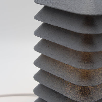 Close-up of a textured gray kengo to lamp against a white wall
