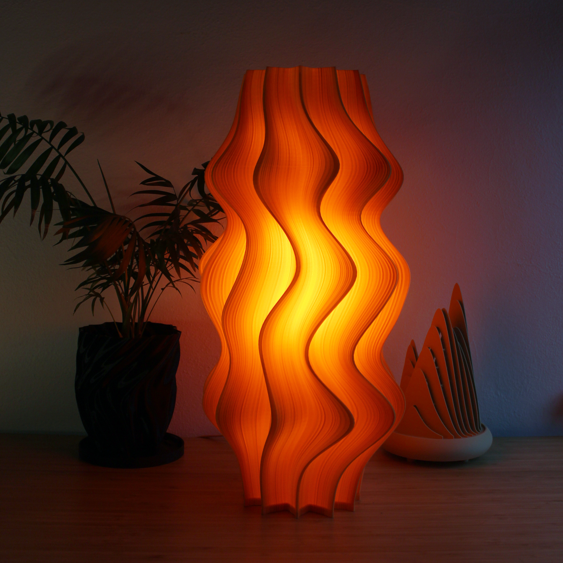 Large Iris Lamp in mandarin orange, 52cm tall with pleated sculptural form and soft glow.