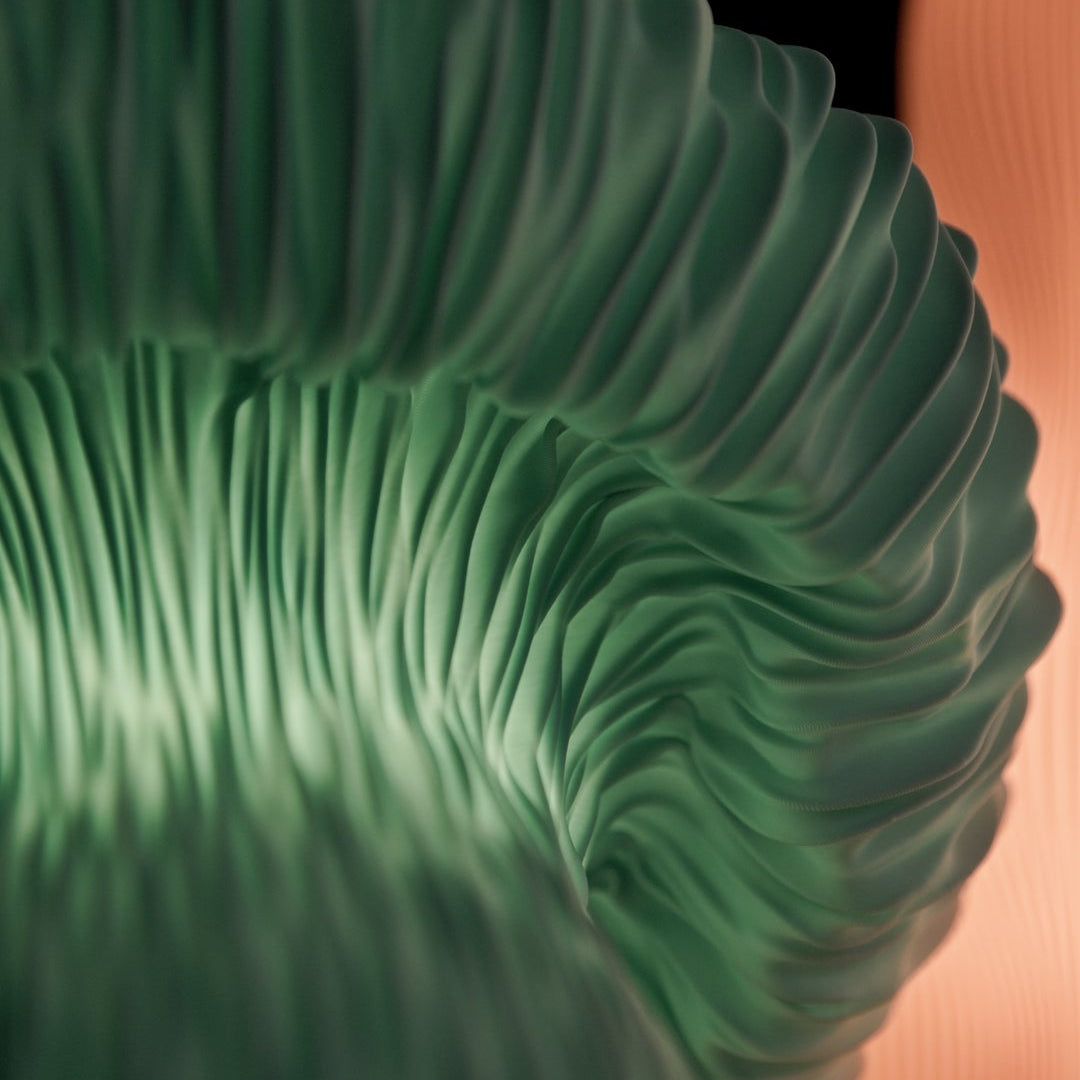 A close-up of a sculptural ribbed surface in translucent green Mycelia Lamp, with layered curved ridges and a dark background.