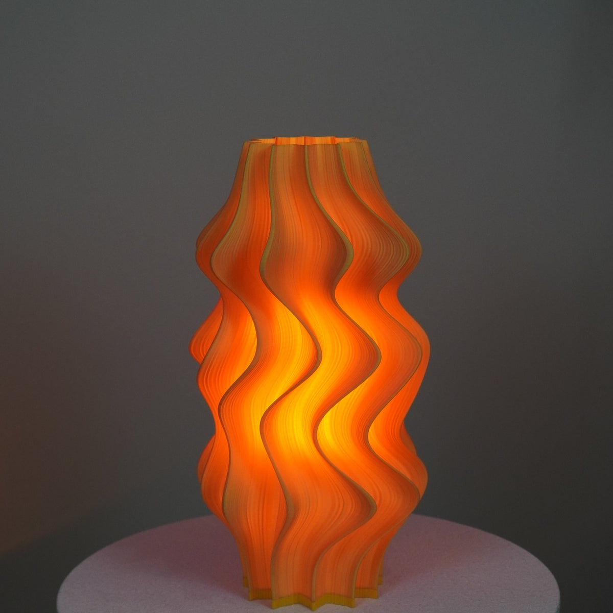 Iris Dual Colour Studio Edition pleated table lamp illuminated with a warm glow