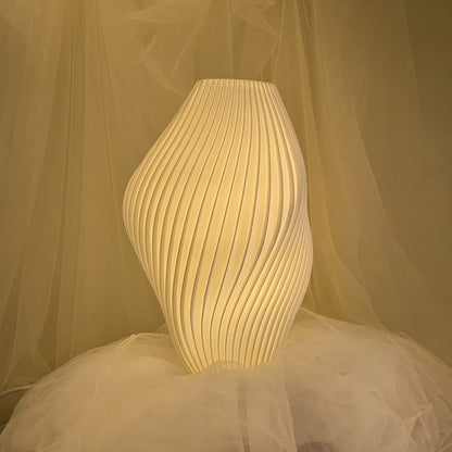 Pleat Lamp Namami, Pleat Lamp glowing softly in curated reading corner