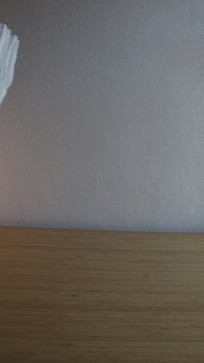 A short, dynamic video showcasing the portability of the cordless Soft Serve Lamp. It's moved effortlessly from a home office desk, to a kitchen counter, and finally to an outdoor balcony at dusk, highlighting its lightweight design and warm, dimmable glow in different settings.